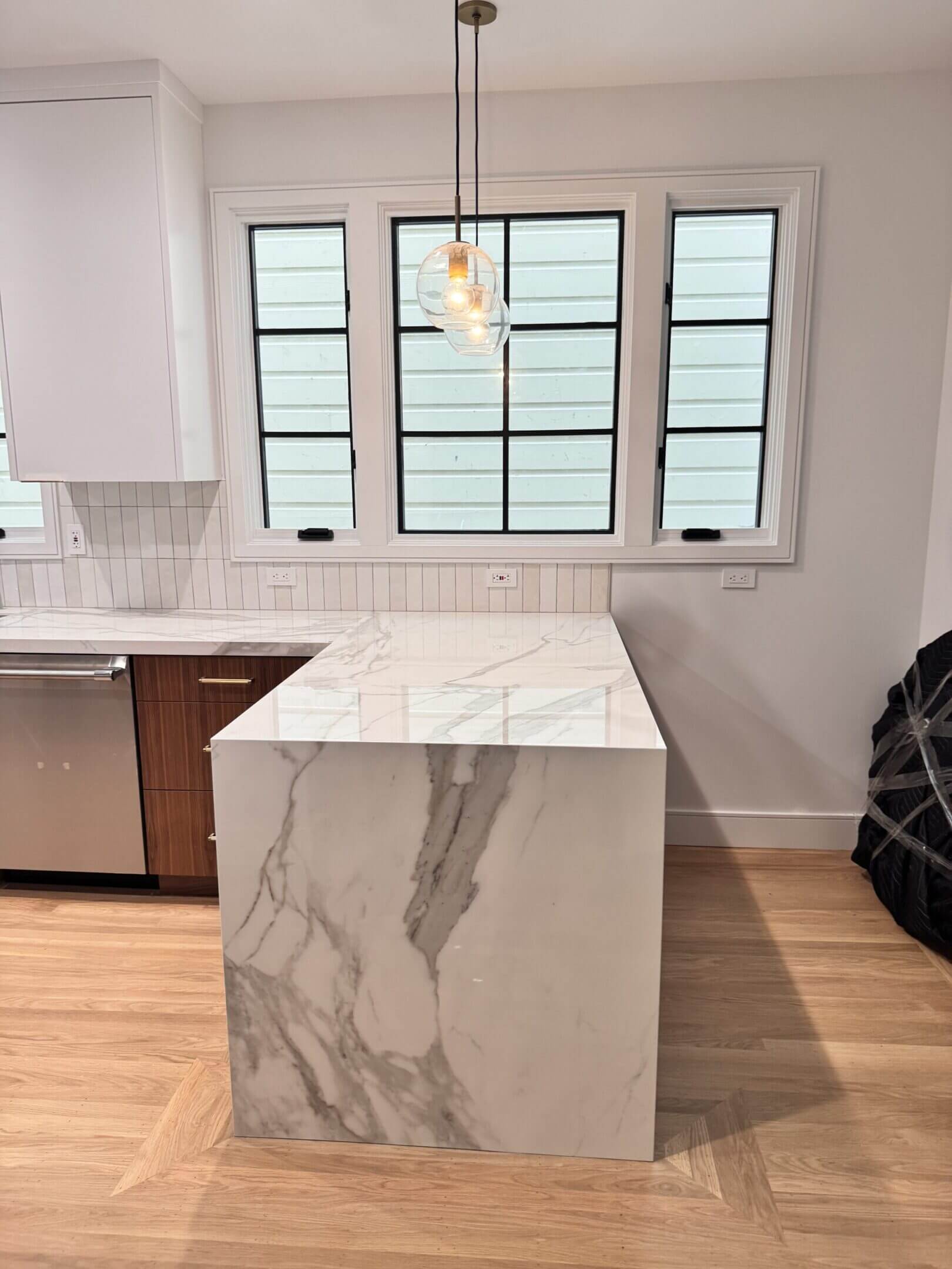 Modern kitchen with marble countertop and wooden floor.