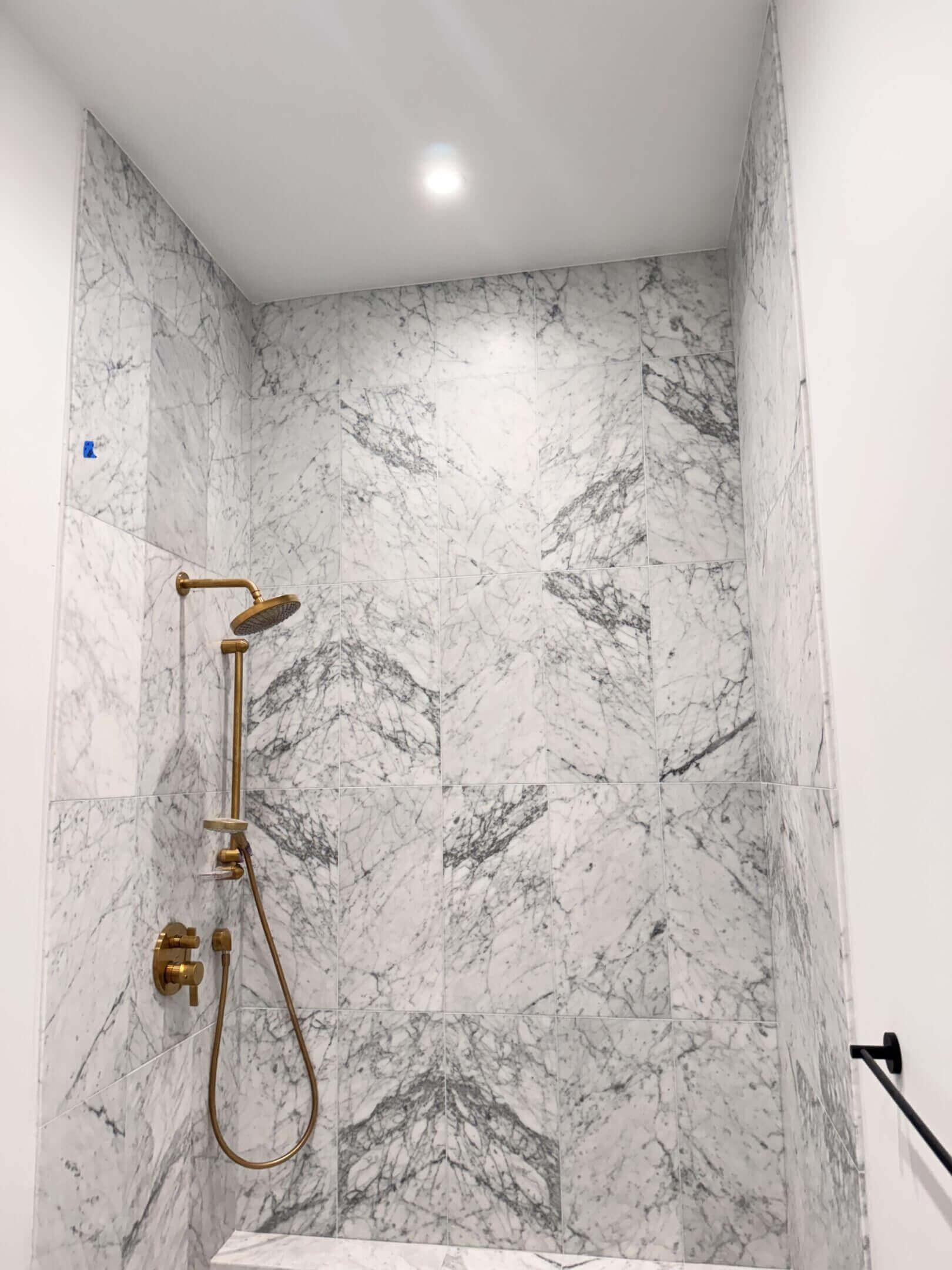 Elegant marble shower with gold fixtures and geometric patterns.