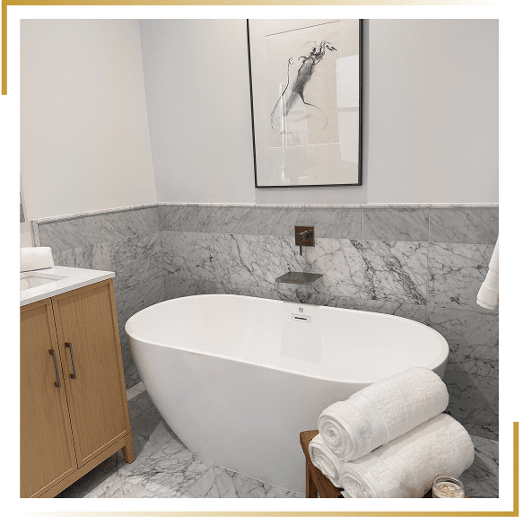 Modern bathroom with a freestanding tub and marble walls.