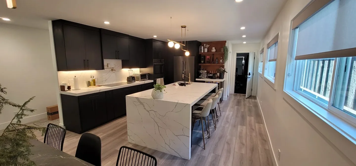Modern kitchen with marble island and bar stools.